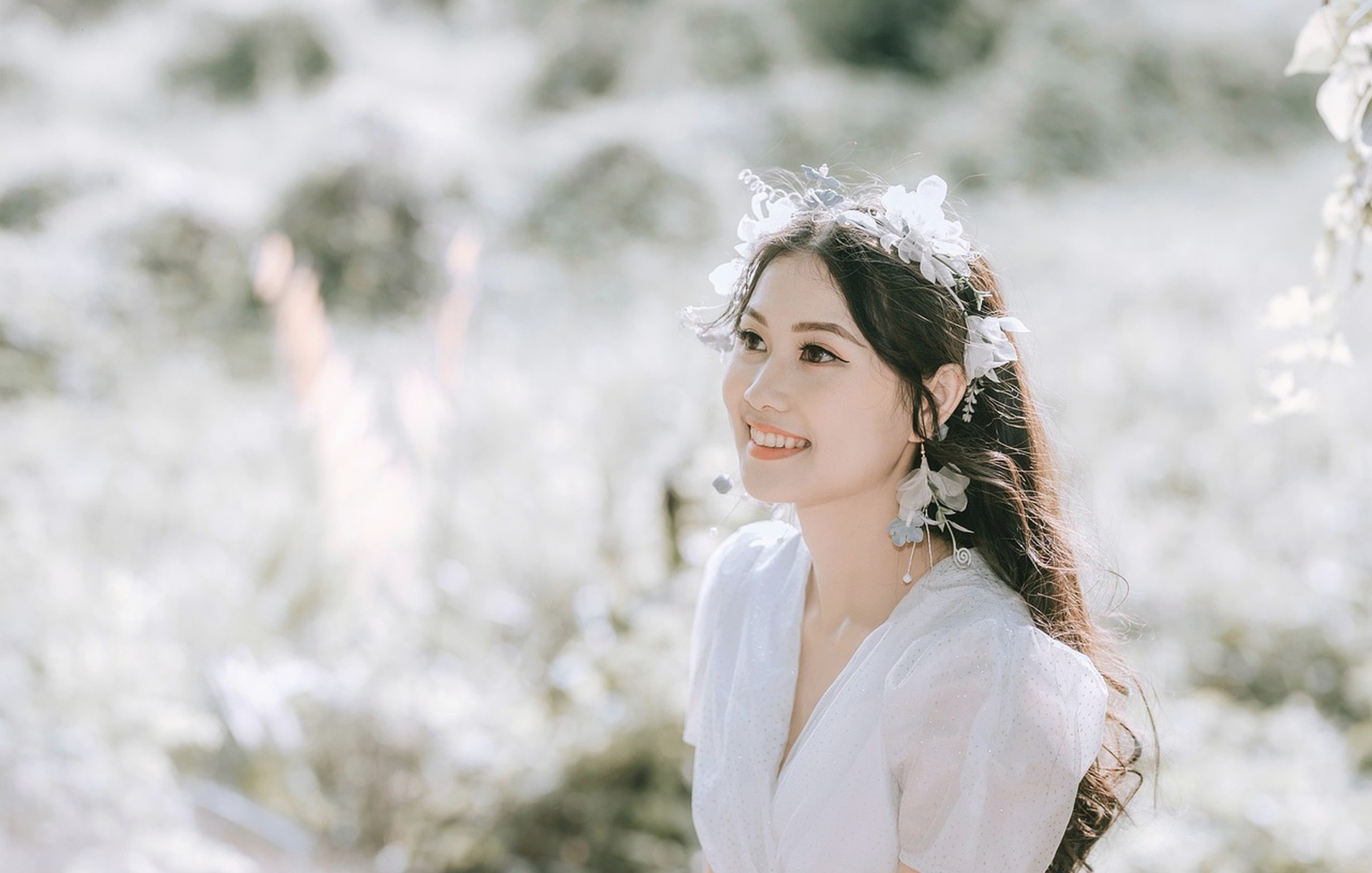 Smiling woman in a soft white dress with floral details